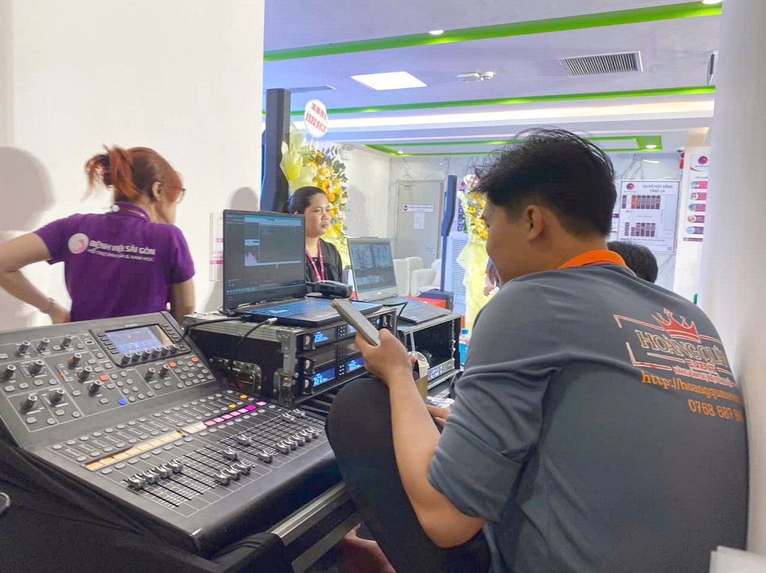 Kỹ thuật viên setup bàn điều khiển âm thanh cho buổi tọa đàm y khoa