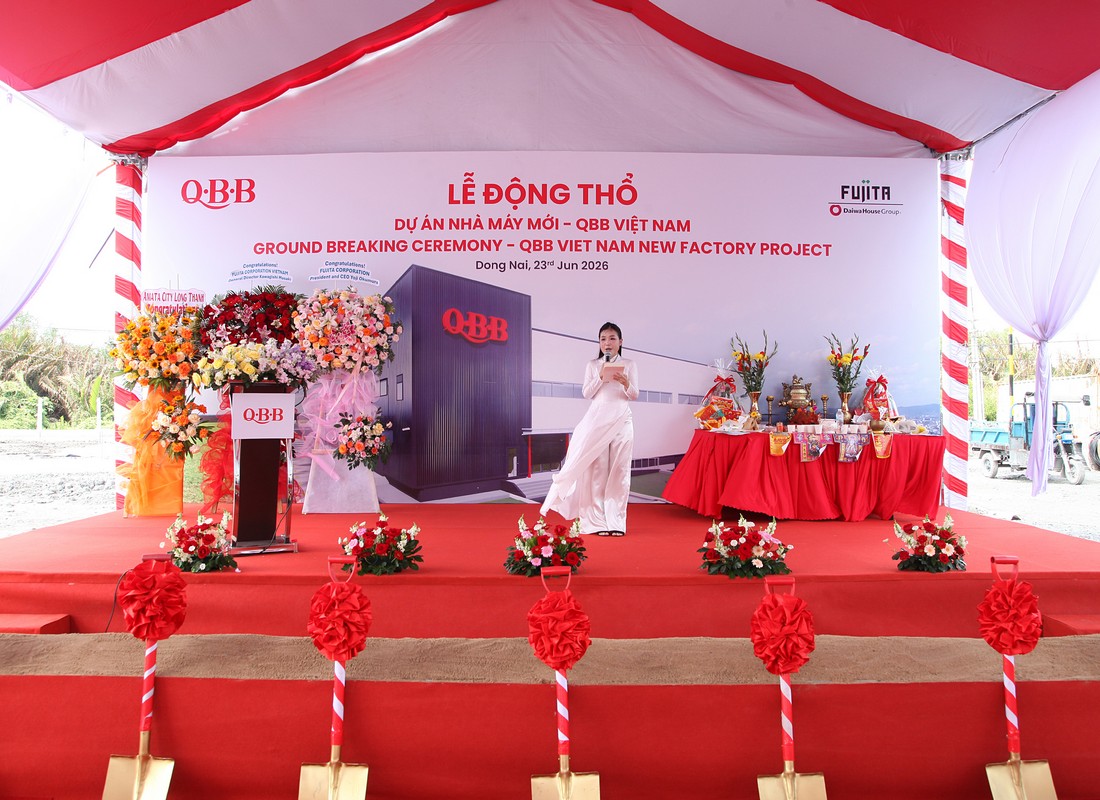 MC mặc áo dài cầm micro và tài liệu dẫn chương trình trên sân khấu QBB.
