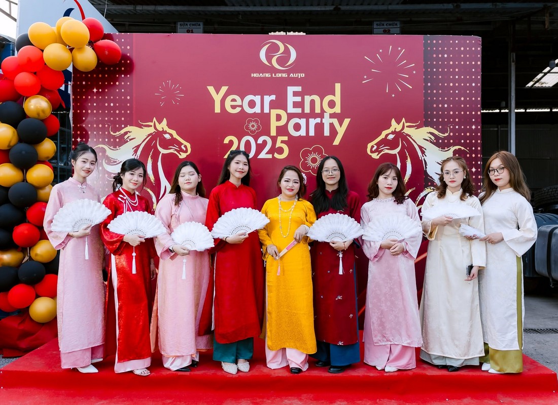 Nhóm khách mặc áo dài chụp hình trước backdrop Year End Party Hoàng Long Auto.
